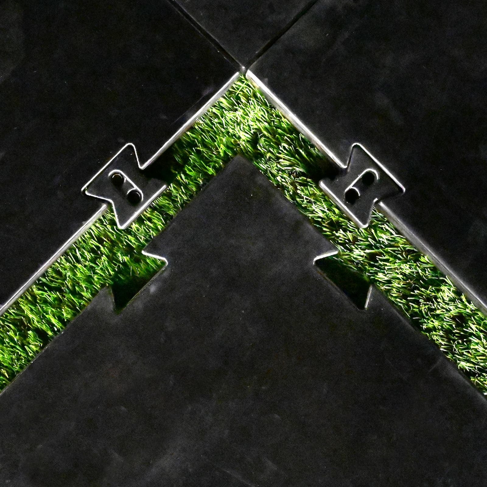 Carl's Place HotShot™ Golf Mat Base - overhead close-up of the bowtie connectors joining two panels over turf