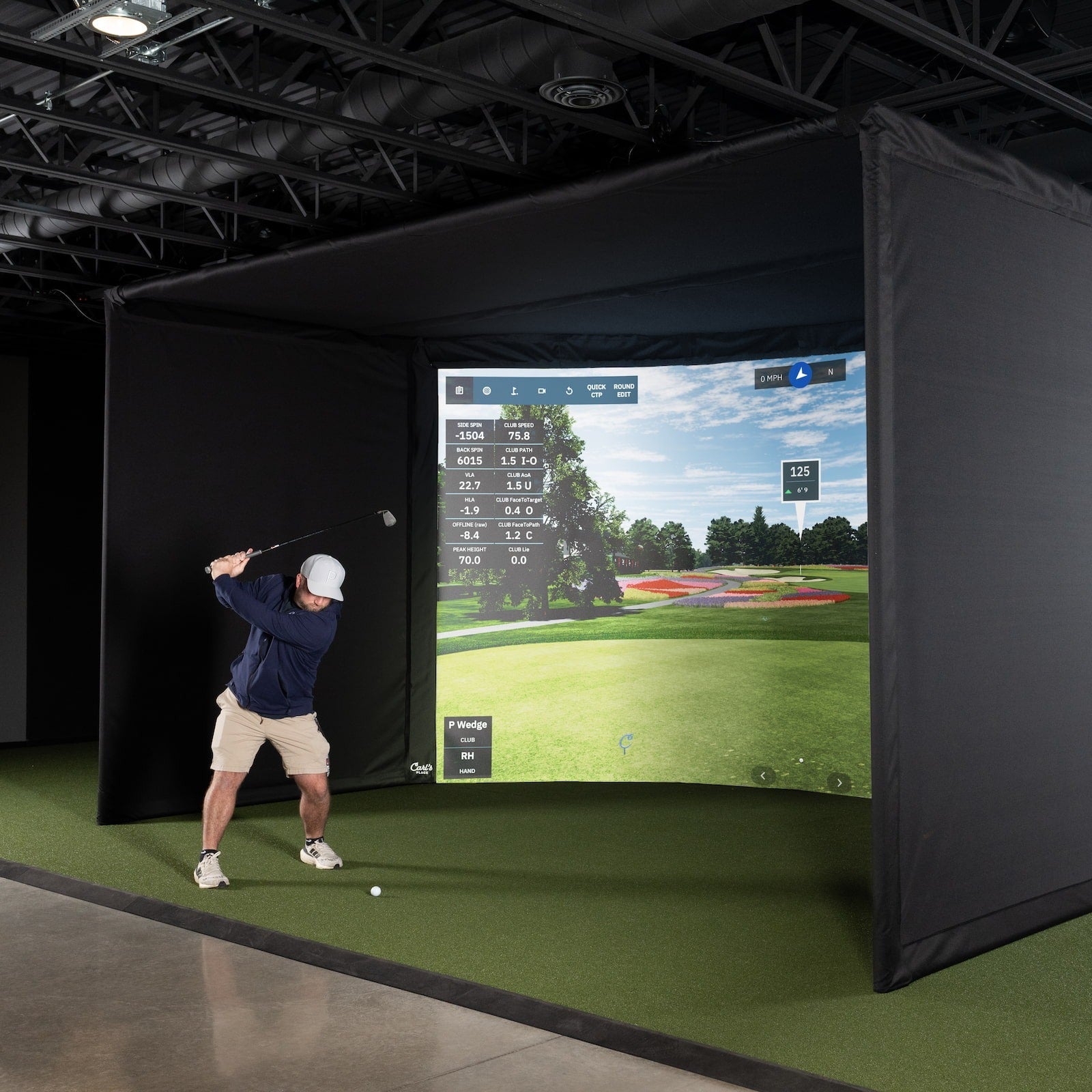 Carl's Place Curved Golf Enclosure Kit with High-Contrast Gray Impact Screen - golfer mid-swing in front of the screen in a studio bay