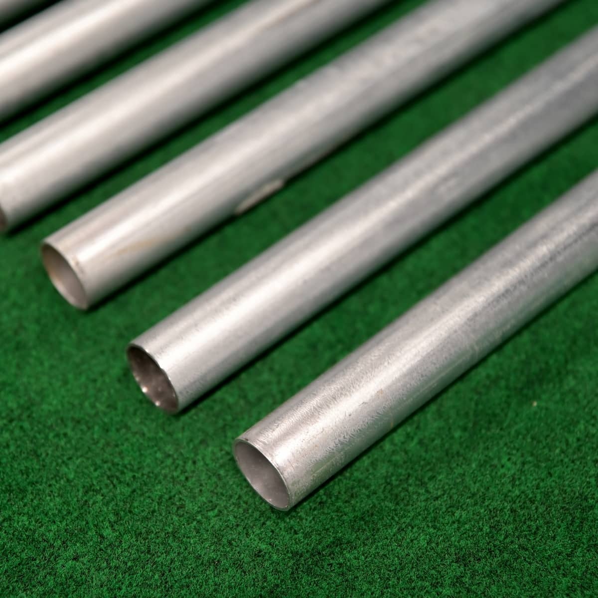 Carl's Place Curved Golf Enclosure Kit with Premium Impact Screen - close-up of the steel frame tubing laid on green turf