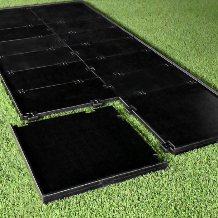 Carl's Place HotShot™ Golf Mat Base - black interlocking rubber panels partly assembled on green turf outdoors