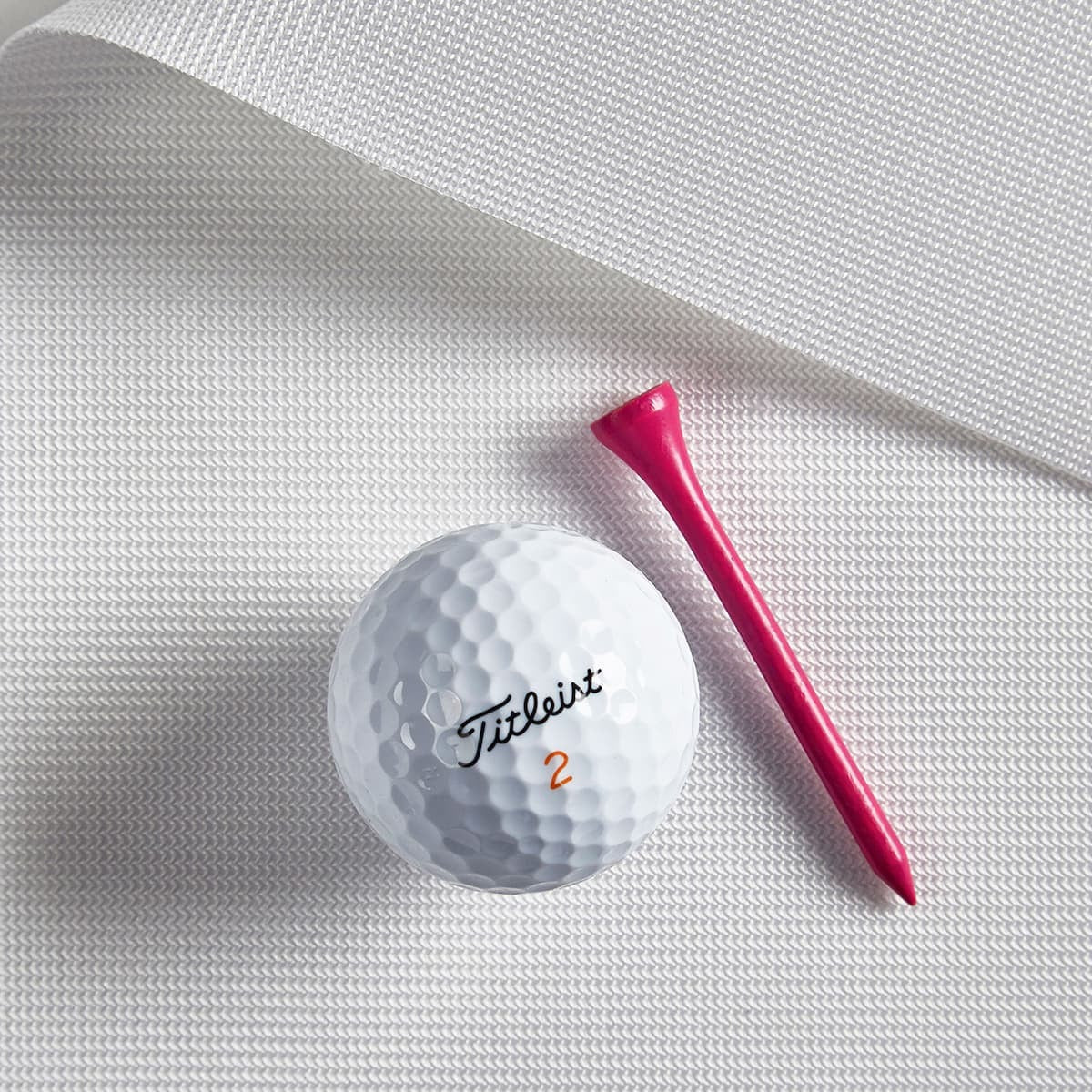 Carl's Place Preferred Impact Screen - golf ball and pink tee resting on the white woven screen fabric surface